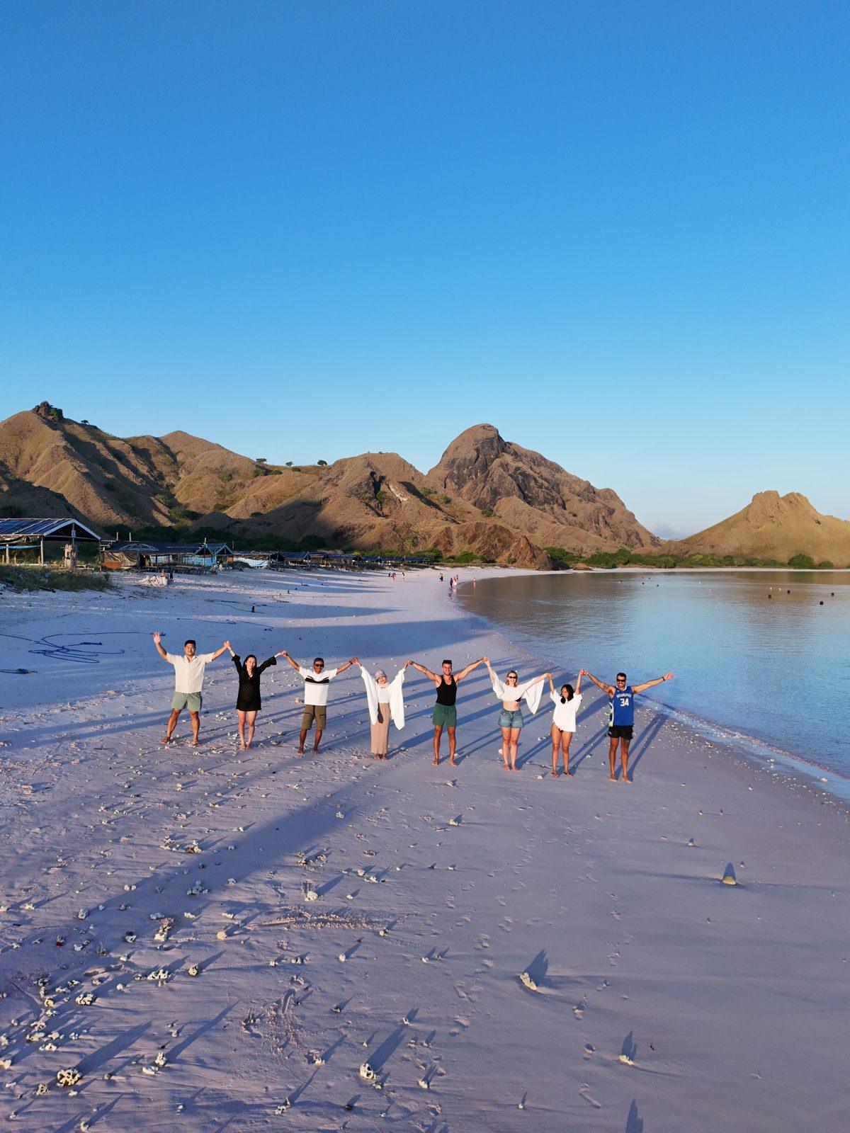 Pink Beach – Group in line on pink sand, hills behind (Foto real de un viaje de Komodo Explorer)